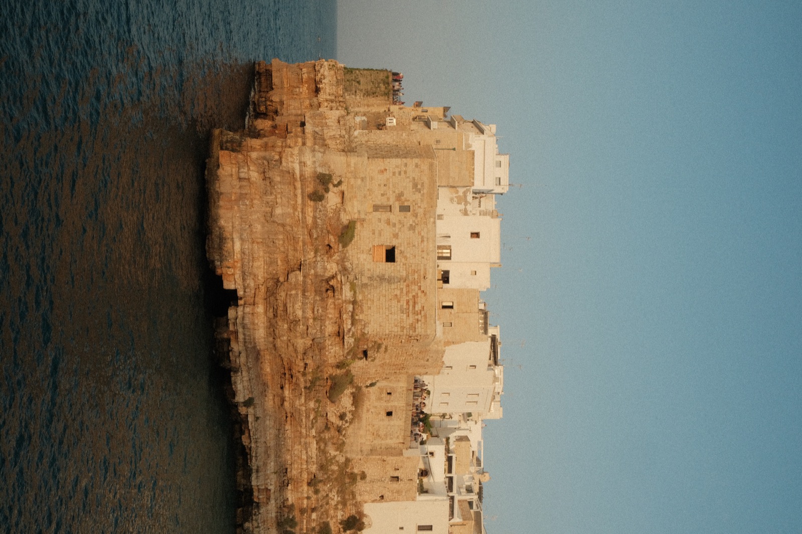 Sunlit stone buildings above the sea in Polignano a Mare, Italy