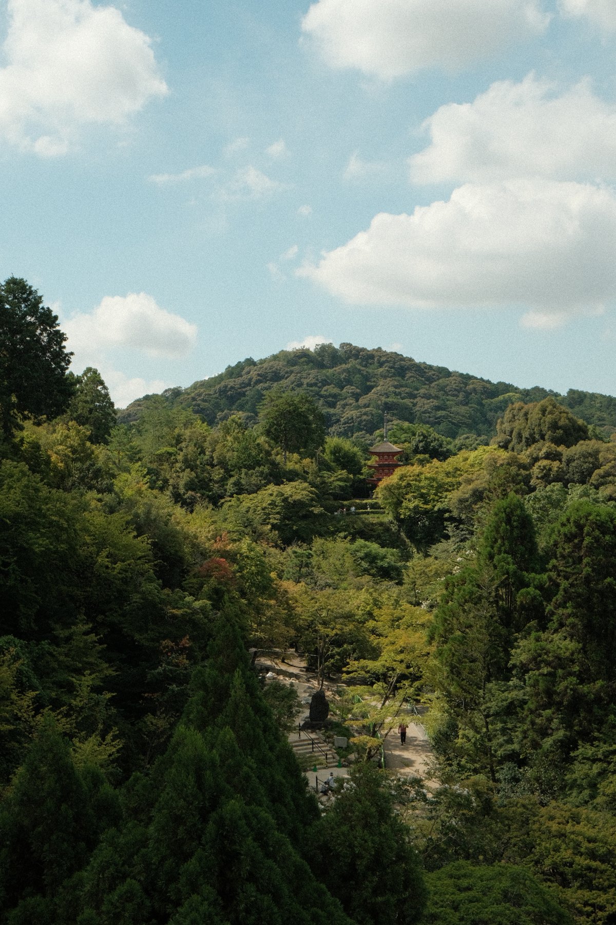 A red pagoda among wooded hills beneath a blue sky in Kyoto, Japan